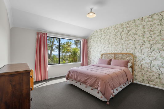 Bedroom with cane bedhead, floor-length curtains, Folia Cream/Pink on all walls, no ceiling shade