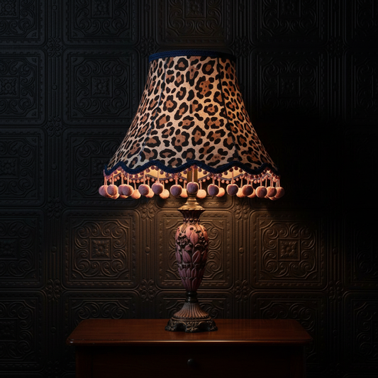 Large animal print lampshade with visible pink pom poms on tassels